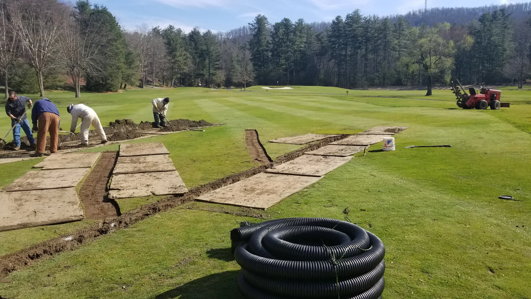 Golf course drainage crew using plywood routes to protect turf