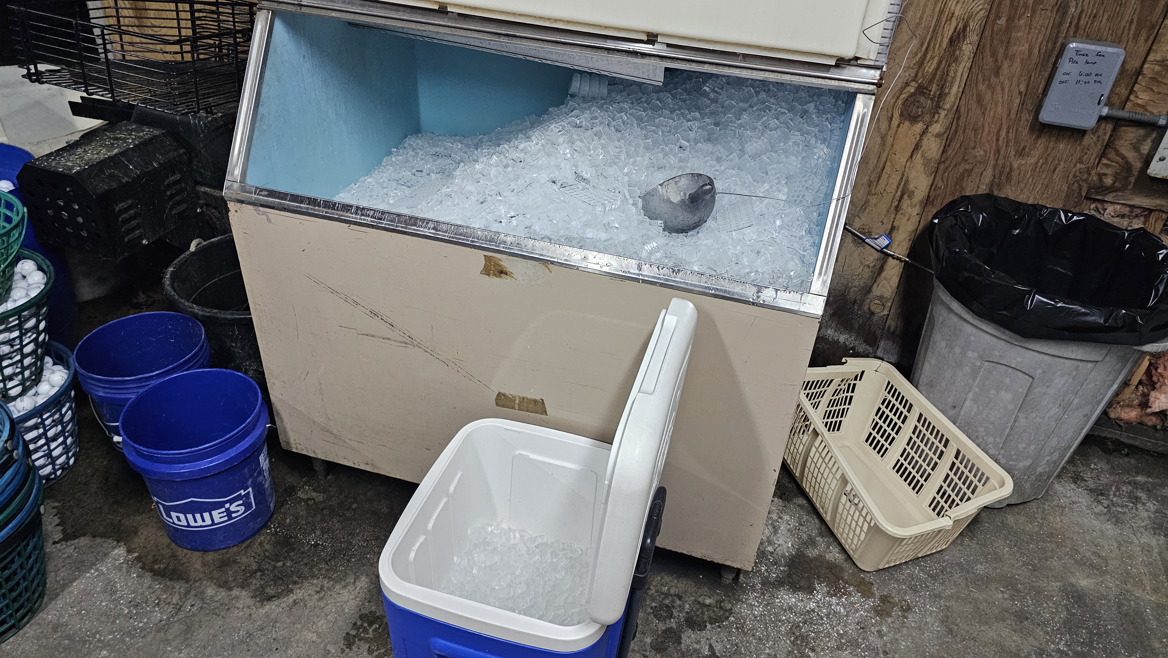 Ice chest with scoop and cooler in a golf maintenance facility.